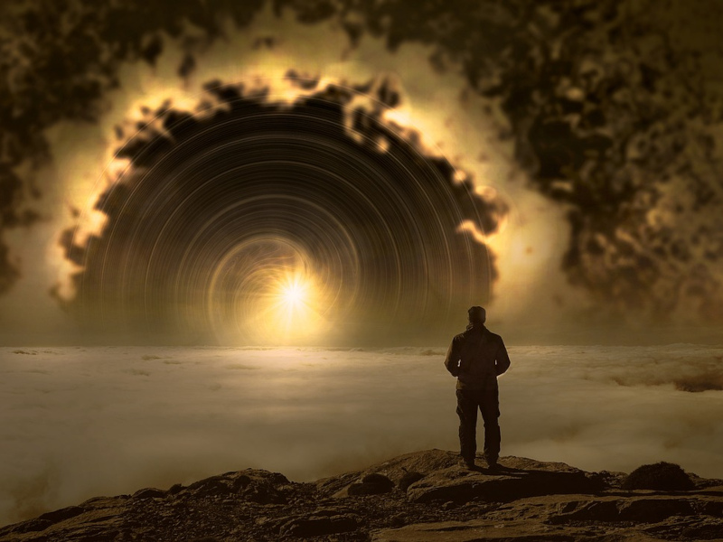 Mann steht auf Fels und schau über Wolken zu Sonne