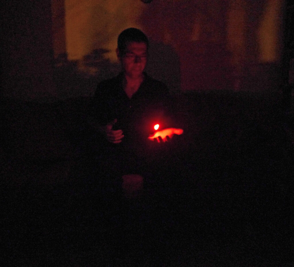 Person im Dunkeln mit einem Licht über der Hand